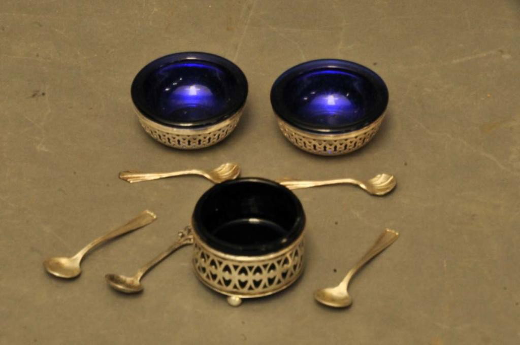 Sterling Silver & Cobalt Glass Salts, Spoons: Three sterling silver salt cellars with cobalt glass liners; two are a pair with circular bodies and openwork, 2" diameter, 7/8"H; one with circular body, openwork, and ball feet, 1 3/4" diameter, 1 1