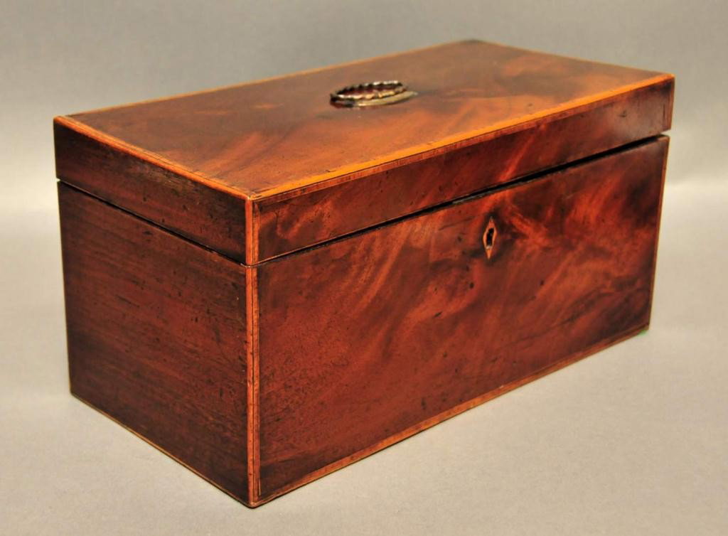 19th Century Mahogany Tea Caddy: Rectangular form with light wood escutcheon and banding; hinged lid opening to two covered tea canisters with hinged lids having light wood banding and a central well containing a footed mixing bowl; 