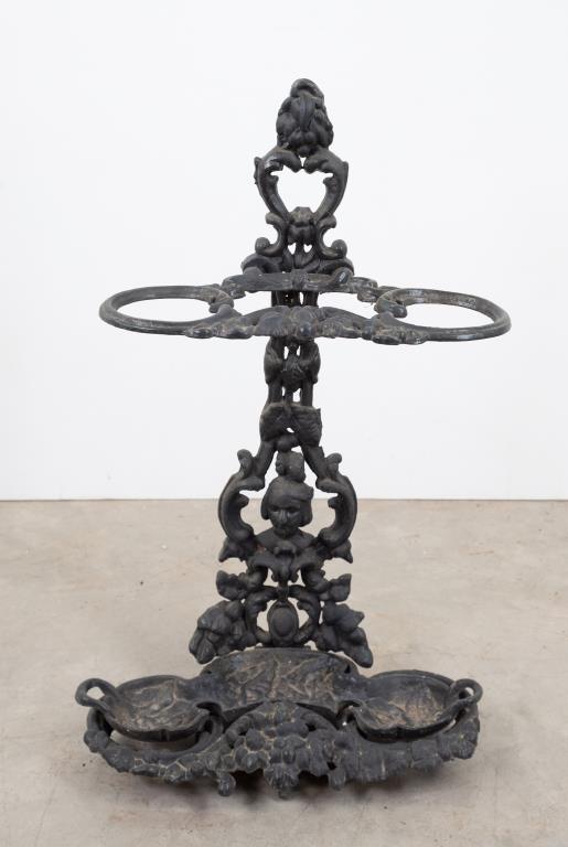 Cast Iron Umbrella Stand: Probably late 19th century; features mask, scroll and leaf castings; cast iron tray in base lifts out; 27 1/2"H, 17"W, 9 1/2"D; good condition---From the estate of Joseph Ewing, long-time antiques dea