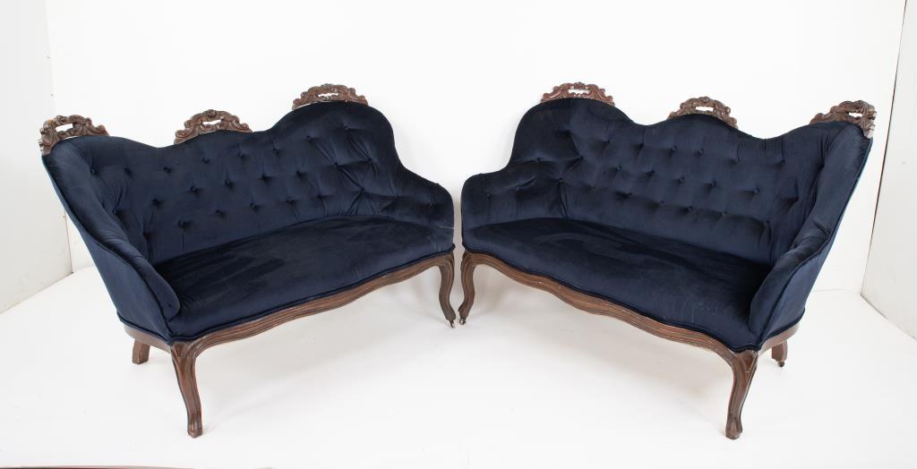 Pair of Victorian Carved Walnut Settees: Late 19th century, each with pierced floral and scroll carvings to crest, serpentine front rail, cabriole legs, later navy blue velvet upholstery with tufted back; one approx. 54"W, 37"H, 25"D, seat 1