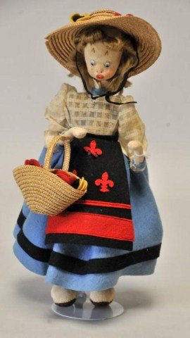 Klumpe Doll, Spain: 11", c. 1950s; female figure wearing a white long sleeve blouse, blue felt skirt with black and red apron having fleur-de-lis decoration, wide brim straw hat trimmed with flowers, carrying a straw bag