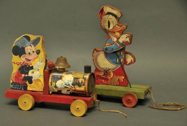 Two Walt Disney Fisher-Price Pull Toys: 1. W.D.P. No. 485 Mickey Mouse Choo-Choo; corrosion to metal parts, pen or pencil marks to graphic of Mickey, other signs of wear and losses; 2. W.D.P. No. 400-500 Donald Duck Drum Major on green base