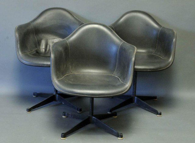 3 Charles & Ray Eames / Herman Miller Chairs: Set of three upholstered armchairs designed by Charles and Ray Eames for Herman Miller, gray fiberglass shells with black vinyl upholstery, enameled steel prong base; each stamped "Herman Miller", one