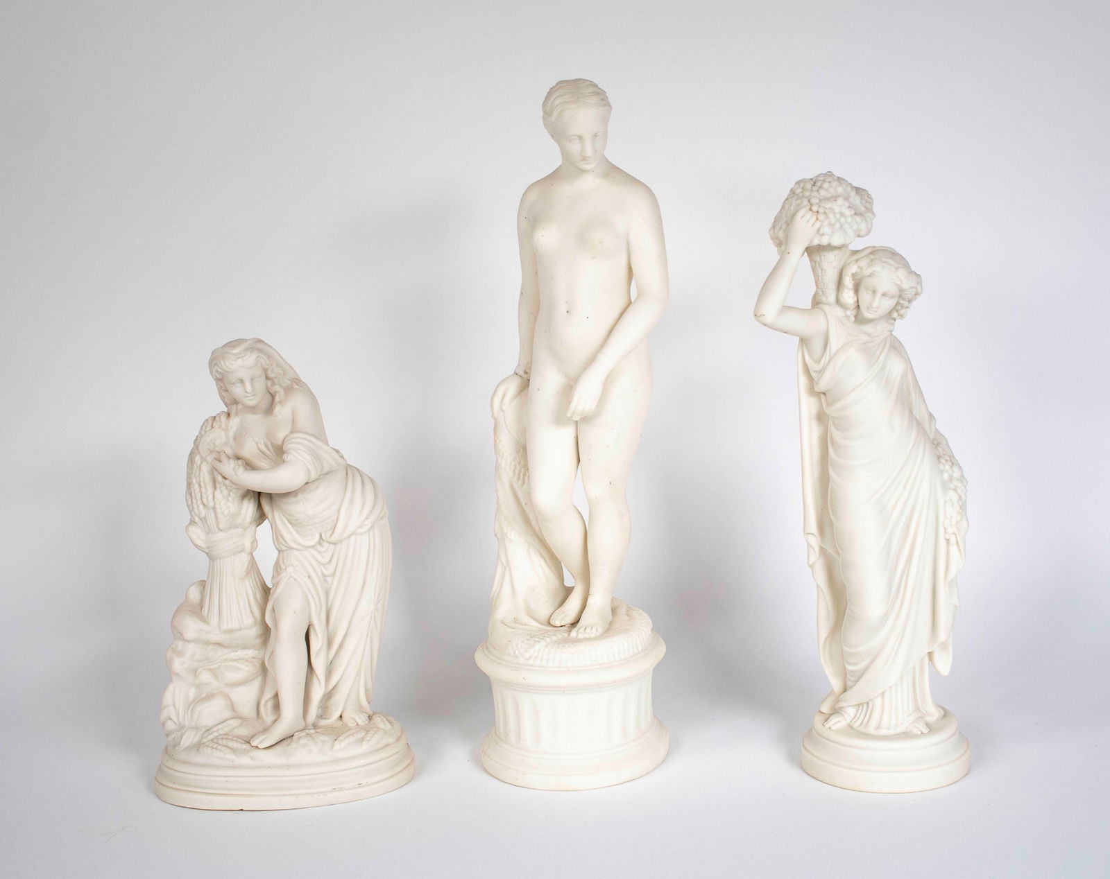 Three Neoclassical Style Bisque Porcelain Statues: 1. "The Greek Slave" after Hiram Powers (American, 1805-1873), lacks chains; 13 1/2"H---2. Statue of Demeter (Ceres), goddess of agrculture, standing with harvest; 9"H, 5 1/4"W---3. Female holding an
