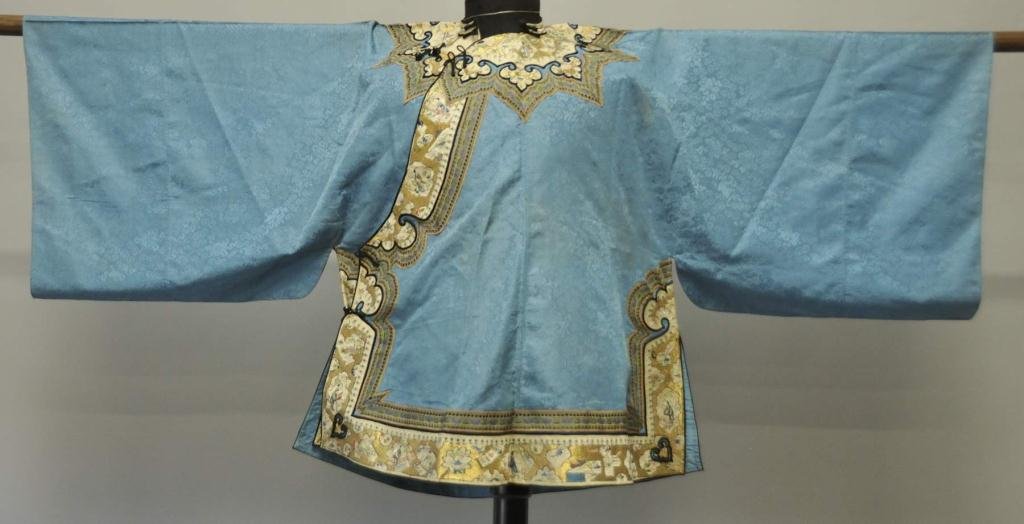Chinese Silk Embroidered Robe: Blue silk damask banded along edges and collar with extremely ornate ivory silk borders having ruyi-head details outlined in black and embroidered with gilt metallic thread background and various scen