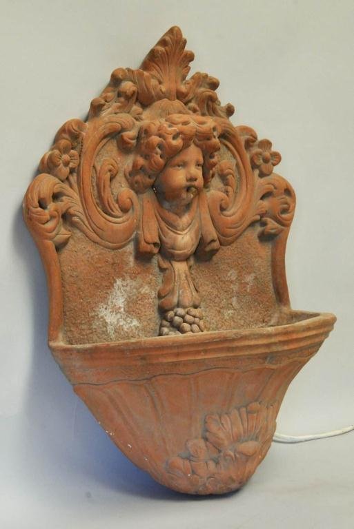 Continental Cast Terra Cotta Wall Fountain: Back cast with mask of young girl and foliate surround, the water spews from her mouth into the basin below; 28"H, 20"W