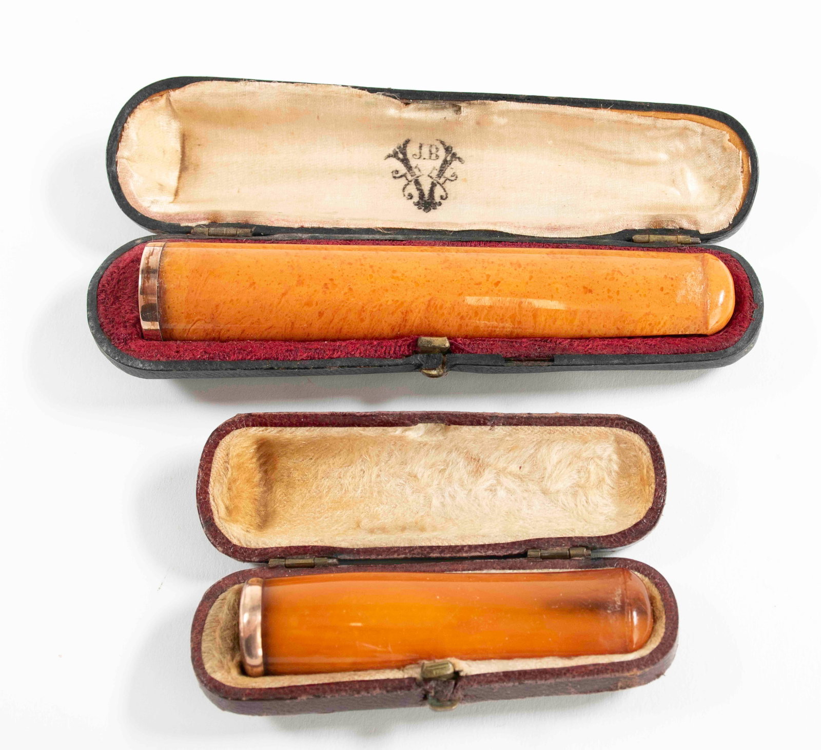 2 Amber Cigar Holders in Original Cases: 1. 4 1/4"L amber cigar holder with gold rim, marked "A (cross) P" and with other small illegible mark, in original case marked "Victor Vinche Bruxelles"---2. 2 3/4"L amber cigar holder with gold rim h