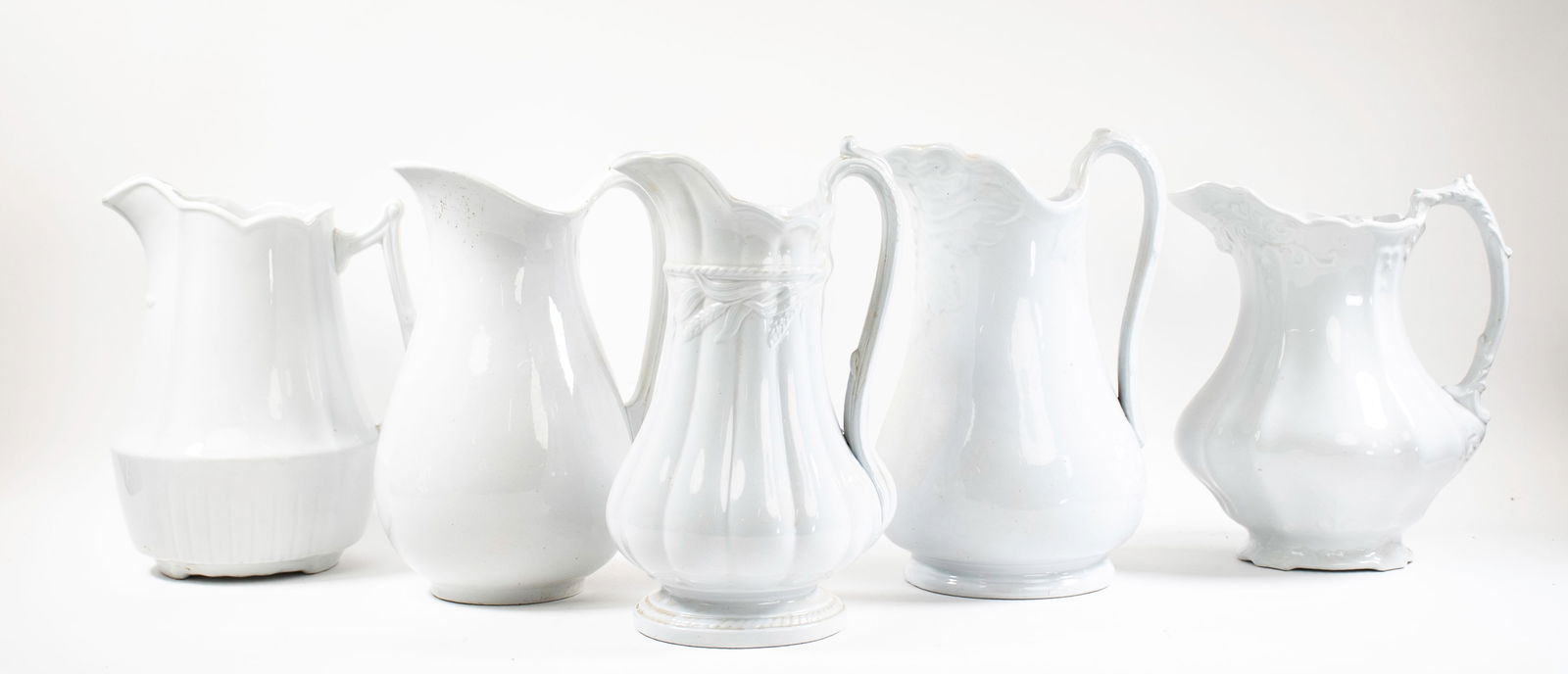 Five English Ironstone Pitchers: Five white ironstone pitchers: Elsmore & Forster having paneled sides and wheat pattern in relief; approx. 13"H; good condition---J. & G, Meakin having a foliate pattern in relief; approx. 13"H; good