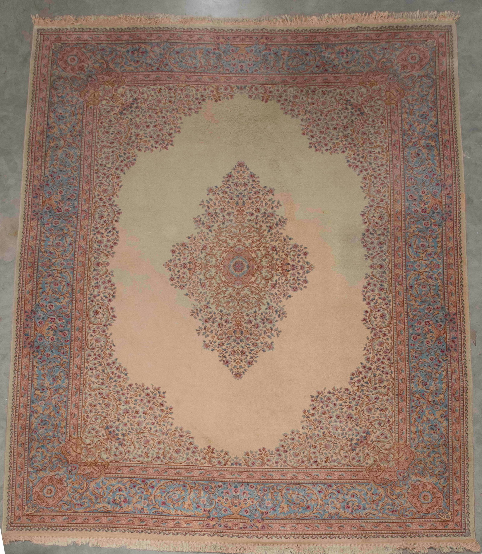 Room Size Carpet, 13'6"L x 10'2"W: Machine woven; center medallion with urns issuing trailing vines and flowers in mauve, blue and brown on a tan ground; matching spandrels; mauve and blue borders; 13'6"L x 10'2"W; good condition with