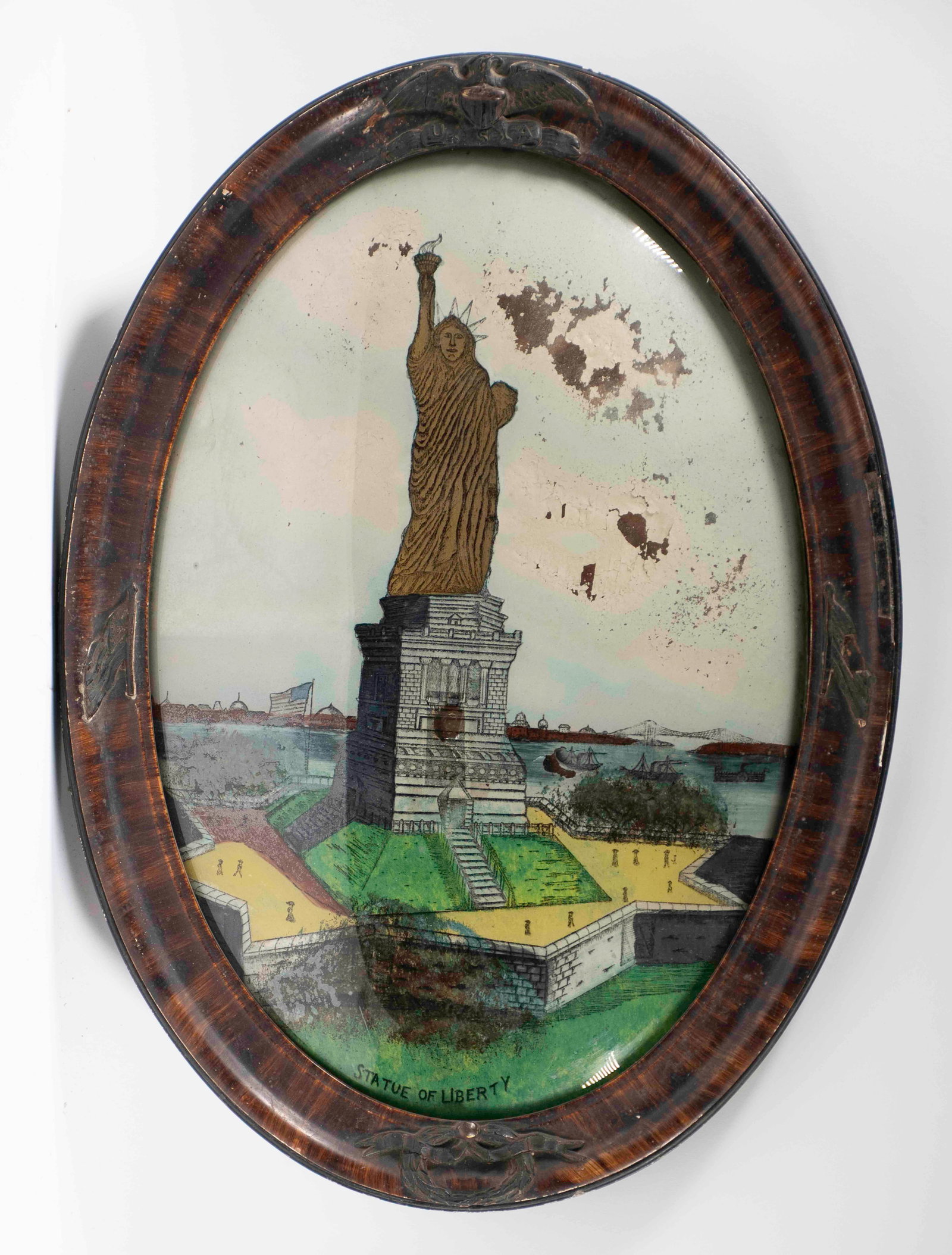 19th C. Statue of Liberty Reverse Glass Painting: Reverse painting on convex glass of the Statue of Liberty with New York City in the background; grain painted wood frame with patriotic motifs of eagle with shield, flags and beribboned wreath; 22 1/2