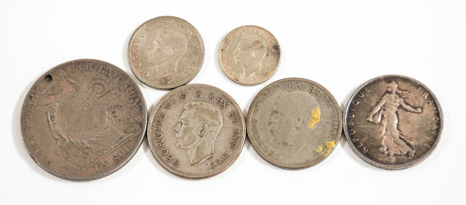 Silver Coins-Guatemala Counterstamped Peru Sol: Six silver coins: 1885 Peru Sol with 1894 Guatemala 1/2 real counterstamp (.900); small hole drilled near one edge---1943 Canada half dollar (.800)---1944 Canada quarter (.800)---1943D Australia