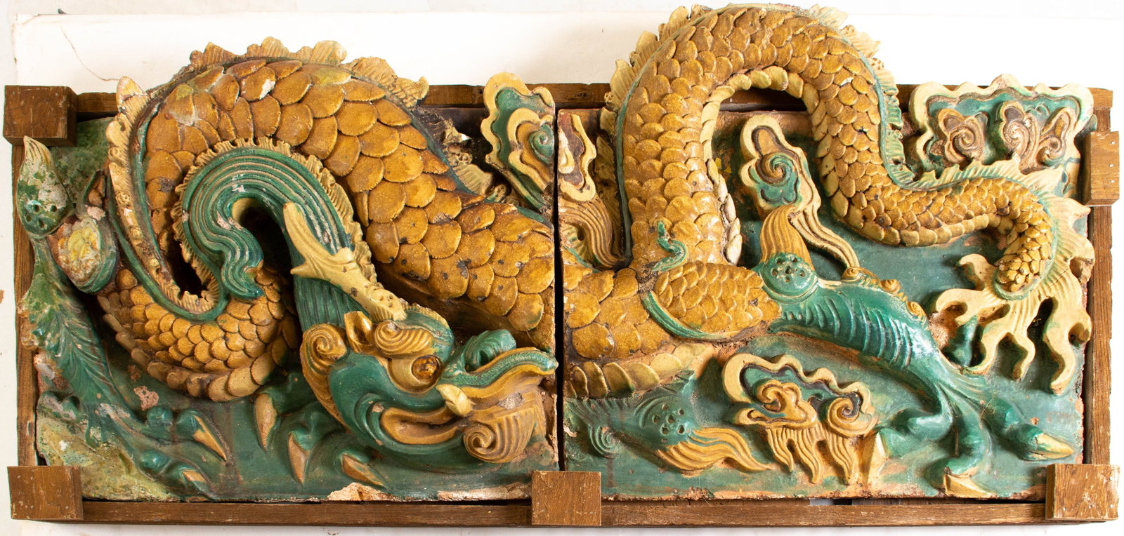 A Large Fahua Two-Part Tilework Dragon Frieze: Ming Dynasty, AD1368-1644; pair of high-relief molded ceramic tiles with a glazed finish depicting a long mustard-yellow writhing dragon amidst turquoise-green background, clouds and accents; typical 