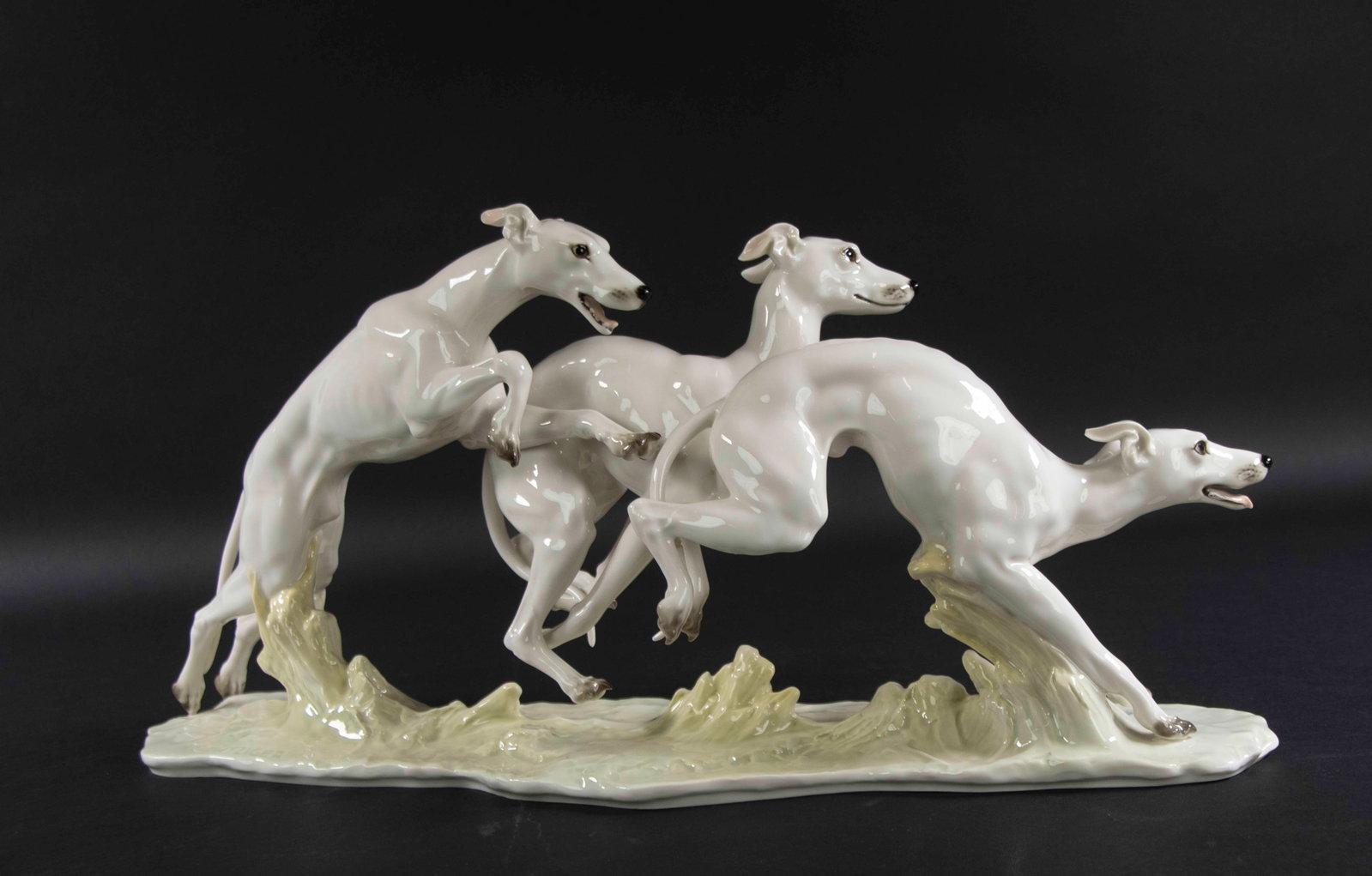 Large Porcelain Figure of Whippets, Hutschenreuthe: Qualifies for in-house shipping---Large porcelain figure of three running whippets, signed by artist "H. Achtziger", base marked for Hutschenreuther and impressed "8224"; 19 1/2"L, 5"D, 9 1/4"H; good 