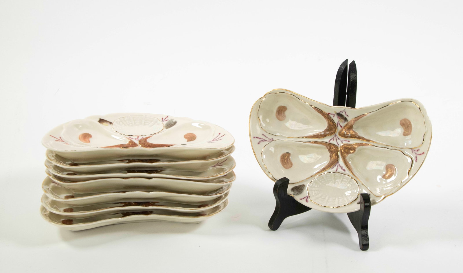 Set of 8 Crescent Shaped Porcelain Oyster Plates: Qualifies for in-house shipping---Each having four oyster wells and a smaller well for lemon or sauce, cream color with painted gilt accents and decorated with painted seashells and aquatic plants, ea