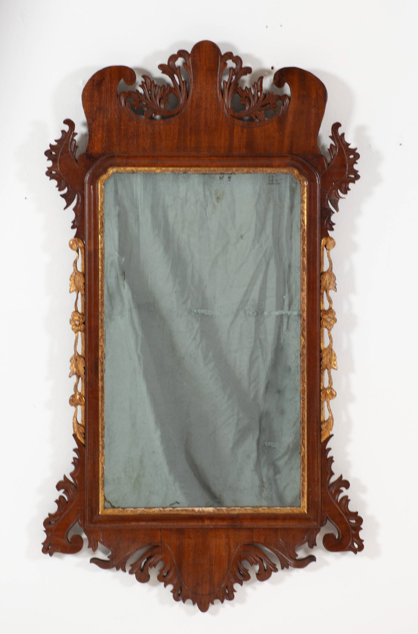 Chippendale Carved Mahogany & Parcel Gilt Mirror: Qualifies for in-house shipping---English/American; 18th century; scrolled pediment featuring a pierced foliate design; sides with carved fruit, floral and leaf gilt streamers; scrolled apron with