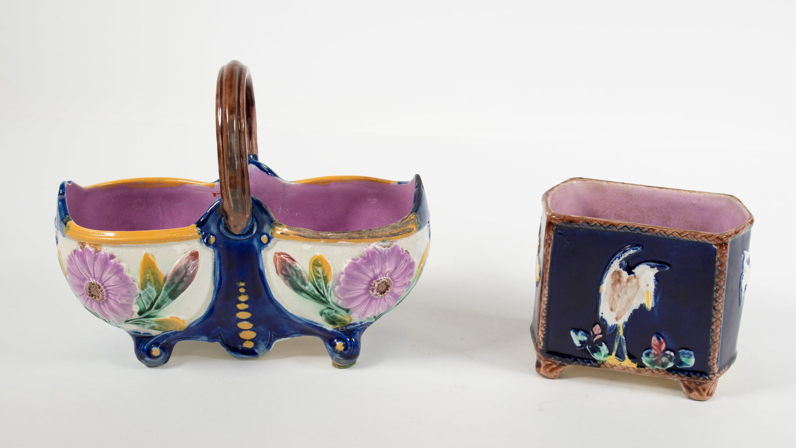 Majolica Cobalt Floral Basket & Small Planter: Qualifies for in-house shipping---Cobalt two-lobed basket with pink-lavender flower motif, pink-lavender interior; 8 1/2"W, 7"H; no glaze on rim of one lobed basket on one side---Small footed planter 