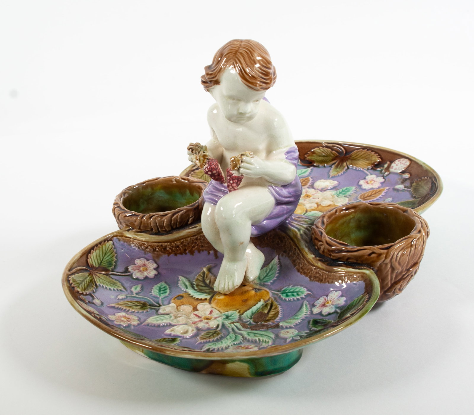 Majolica Figural Strawberry Server: Qualifies for in-house shipping---Double sided dish centered with full figure putti seated and holding a cluster of grapes in each hand; a basket well on each side of putt;, interior of dish