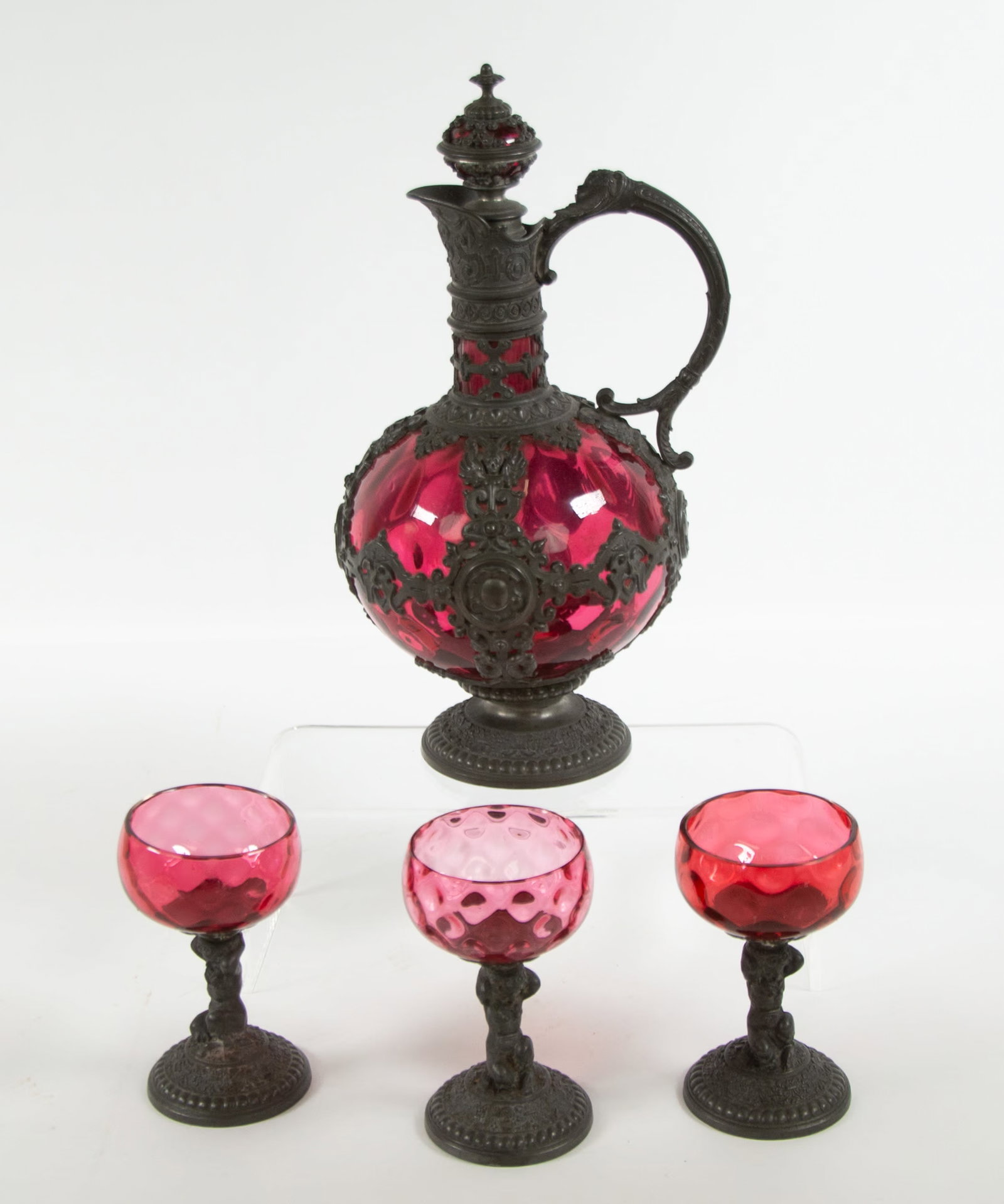 Continental Pewter Overlay Glass Claret Jug: Qualifies for in-house shipping---19th century, pewter-mounted glass claret jug and stopper with three goblets: Claret jug and stopper featuring cranberry glass with an ornate pewter cage mount