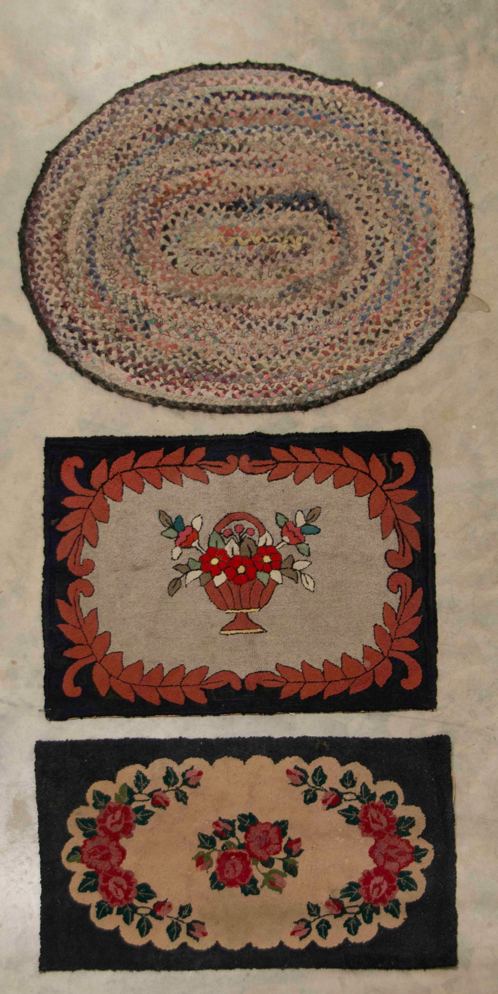 Two Hooked Rugs and Braided Rag Rug: Qualifies for in-house shipping---Three late 19th / early 20th century small rugs: 1. Hooked rug featuring a basket of multi-colored flowers on a grayish / tan ground with scrolled foliate surround,