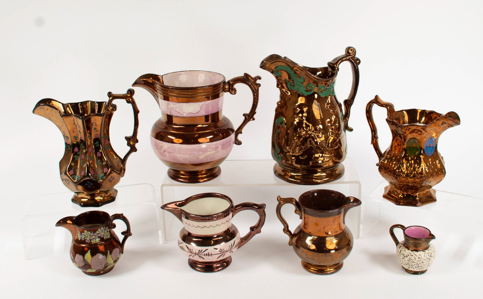 8 English Copper Lustre Decorated Pitchers / Jugs: Qualifies for in-house shipping---Eight decorated copper lustre ceramic jugs, all with decorative handles, including: 6 1/2"H with mottled pink bands; chip to side of spout, minor glaze chips to rim,