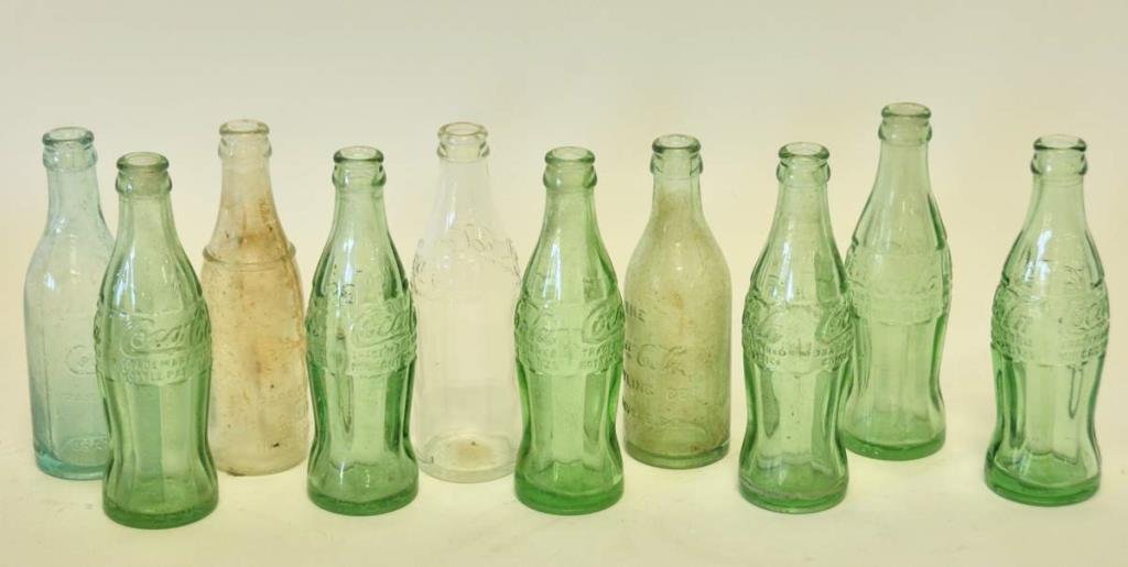 10 S. Carolina Coca-Cola & Ginger Ale Bottles: Seven Coca-Cola bottles with South Carolina cities: two Greenwood, one Darlington, one Orangeburg, one Greenville, three Laurens; one straight sided Coca-Cola bottle with "Coca-Cola" in script on base