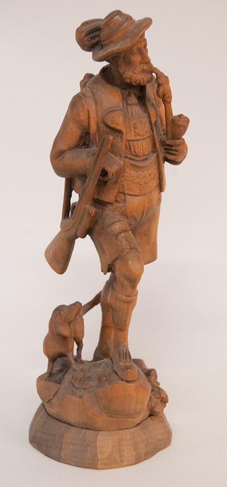 Oberammergau Carved Wood Figure: Woodcarving of a hunter smoking a pipe and hiking with his dog, carrying a rifle on his shoulder and a pack on his back, stamped on base \"Anton Fischer Oberammergau\", 12\"H