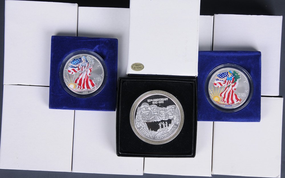12 Silver Coins: Including: eleven American Eagle silver dollars in full color (7) 1999, (4) 2000 and (1) Mount Rushmore 50th Anniversary Great Land of Liberty 2 troy ounces .999 fine silver (Inv. 20)