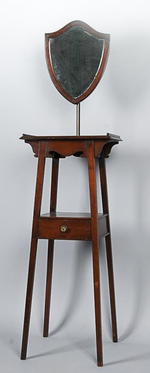 Regency Mahogany Shaving Stand Shield shaped mirror on: Shield shaped mirror on adjustable brass standard, galleried top over shaped apron, lower shelf with finely dovetailed drawer, mid 19th century; 13 1/4"D, 18"W, 66"-76"H; signs of wear commensurate wi