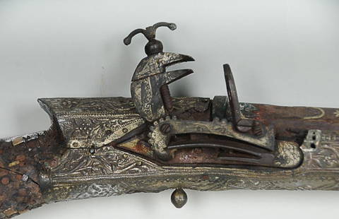 18th C. Turkish Miquelet-Lock Rifle Extensive inlay to: Extensive inlay to barrel, applied bands chased with scrollwork and foliage in relief on stock and barrel, remnants of horn chequerwork on stock, 59 1/2"L; losses to stock and chequerwork, rust to loc