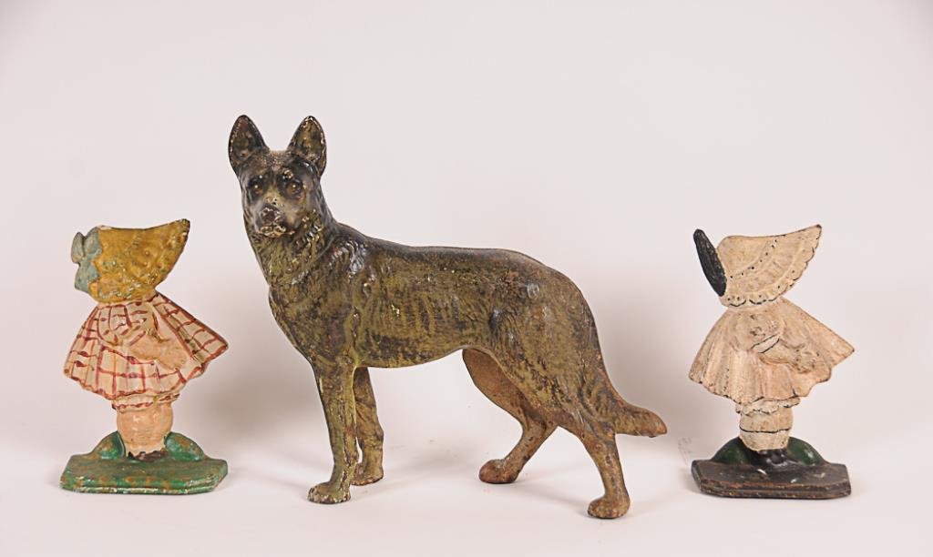 3 Painted Cast Iron Figural Doorstops Including: Two: Including: Two sunbonnet girls, one dressed in white with black trim and matching bonnet with feather, other in red and white plaid dress and yellow bonnet with blue ribbon, 6"H, 3 5/8"W--German sheph