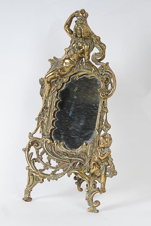 Art Nouveau Table Mirror Elaborate Art Nouveau: Elaborate Art Nouveau openwork gilt metal frame with mirror, surmounted on left by partially draped nymph and with putti lower right, folding supporting leg to back, marked on back "No. 1007.P"; 7 3/4