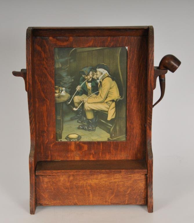 Gentleman's Quarter-Sawn Oak Smoking Cabinet: American, early 20th century, hanging quarter sawn oak cabinet, storage compartment with hinged lid beneath a lithograph of two gentlemen smoking in a tavern, pipe holders mounted to each side, with o
