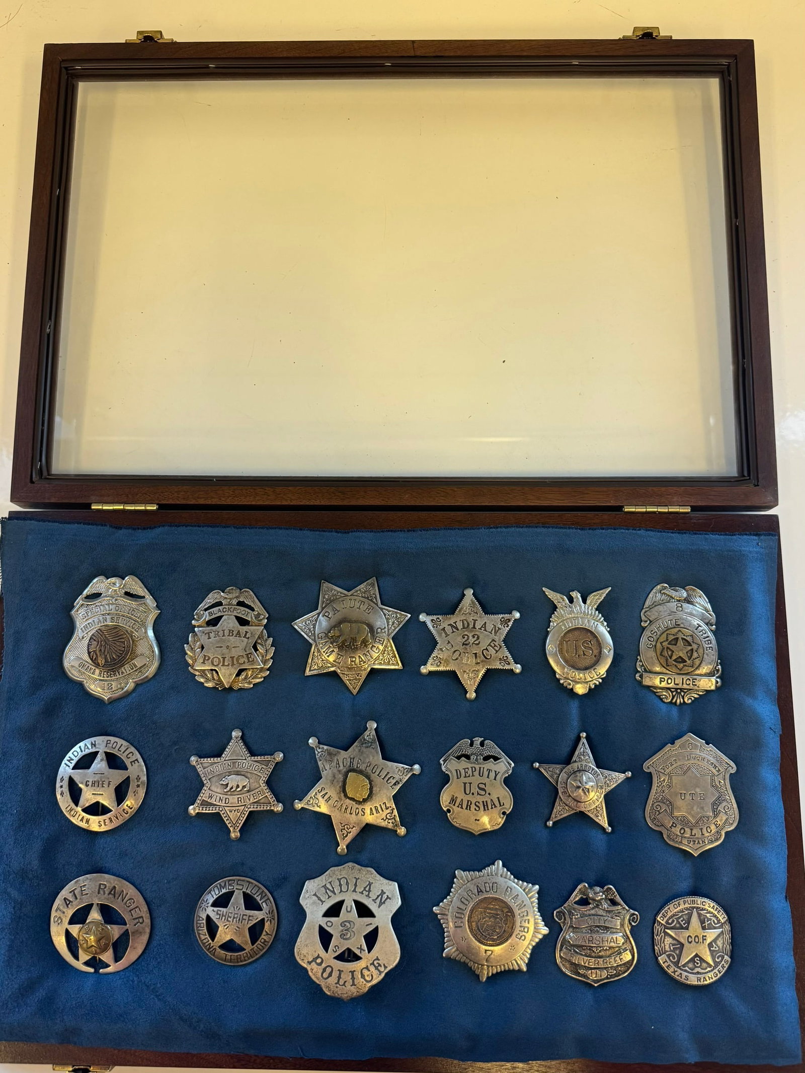 WESTERN LAW MAN BADGE COLLECTION: DECORATIVE WESTERN LAW MAN BADGE COLLECTION.INCLUDES APACHE POLICE, INDIAN SERVICE, TEXAS RANGERS, U.S. MARSHAL AND OTHERS.MID-LATE 20TH CENTURY (1950'S)ALL DISPLAYED IN A NICE WOODEN DISPLAY BOX.PROV