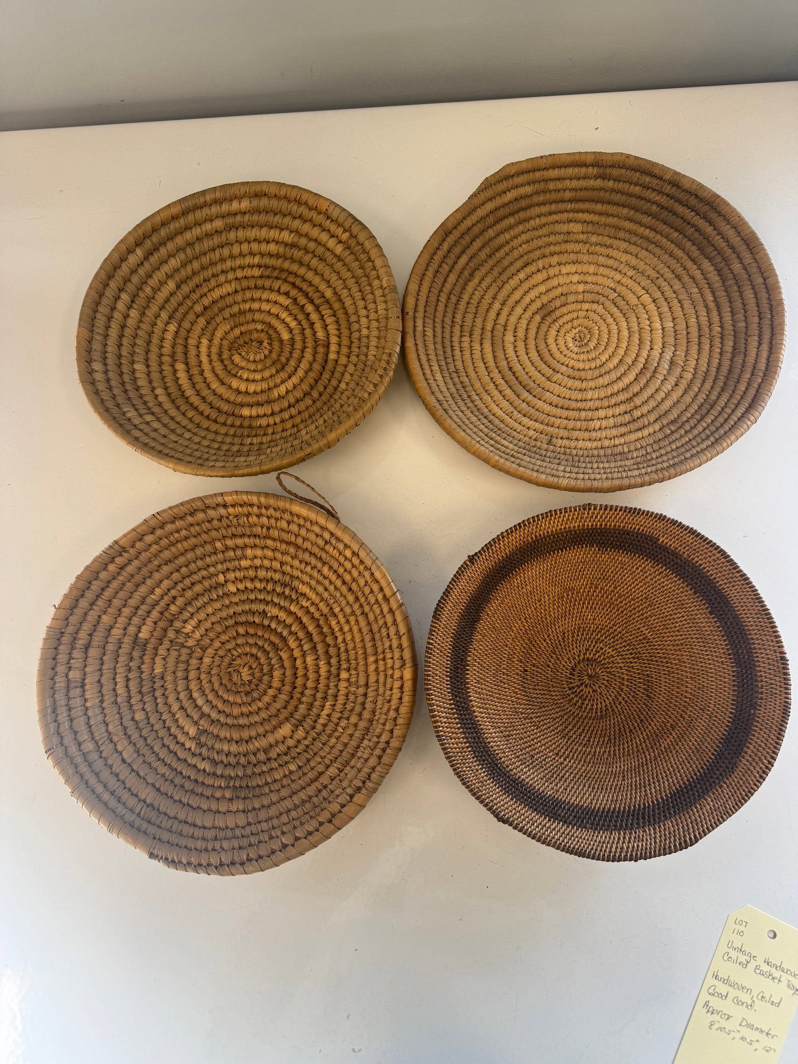 VINTAGE HANDWOVEN COILED BASKET TRAYS: THESE BASKET TRAYS ARE HANDWOVEN COILED IN GOOD CONDITION.APPROX DIAMETERS OF BASKET TRAYS - 9", 10.5" , 10.5", 12"PROVENANCE: ESTATE OF DOUG DIVISH NORTH EAST OHIO