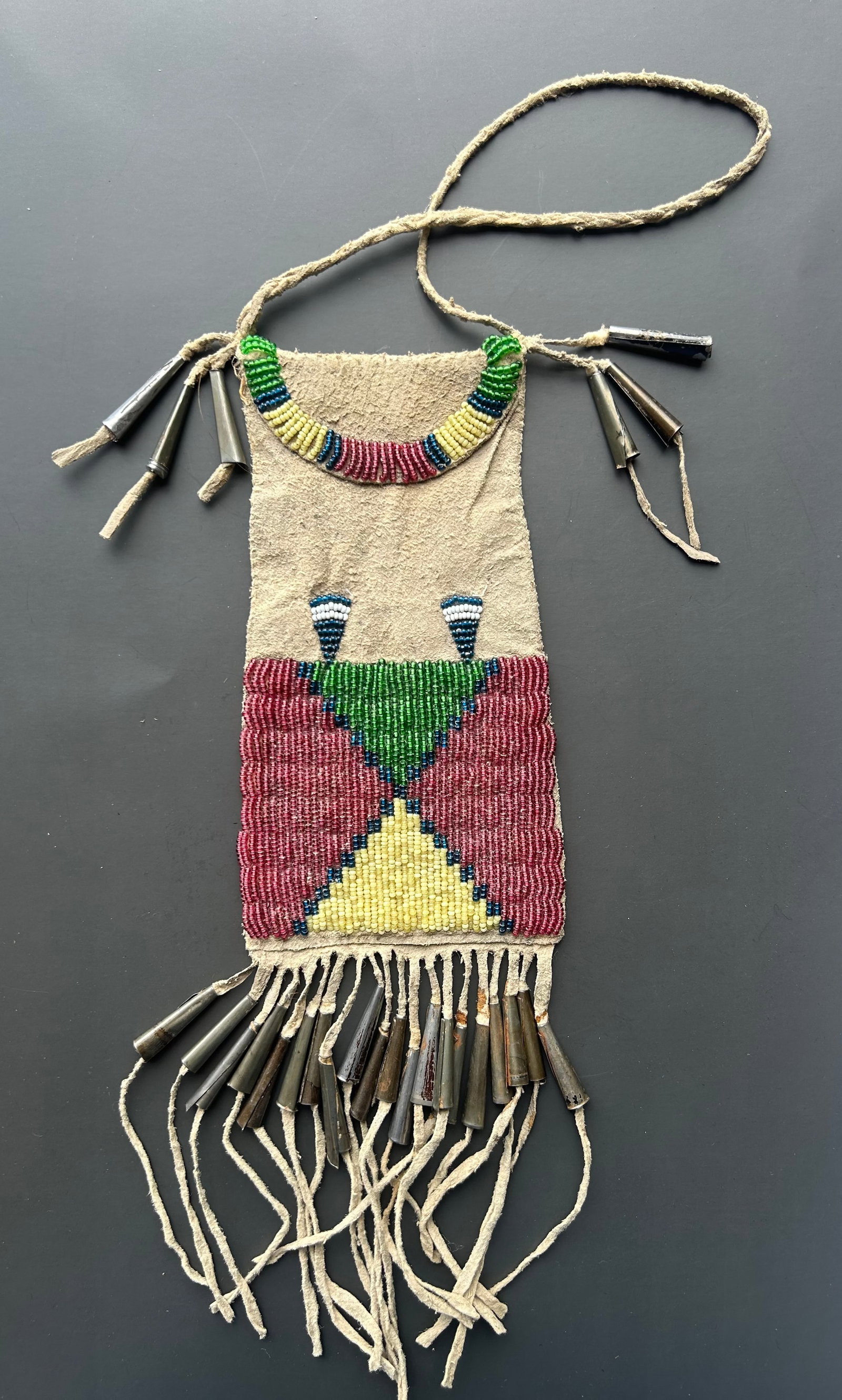 ANTIQUE PLAINS STYLE NATIVE AMERICAN BEADED POUCH: STRIKING AND HIGHLY COLLECTIBLE NATIVE AMERICAN BEADED POUCH FEATURING VIBRANT GEOMETRIC BEADWORK ON SOFT TANNED HIDE WITH NUMEROUS HANDMADE ROLLED METAL TINKLERS. POUCH MEASURES APPROX. 6.5" X 3.5" (
