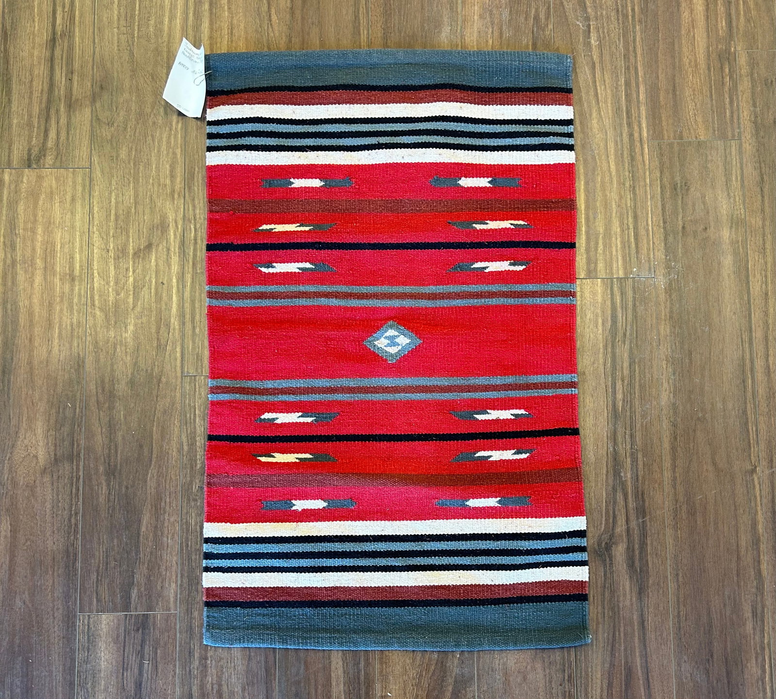 SOUTHWESTERN NAVAJO STYLE HANDWOVEN RUG: VIBRANT HANDWOVEN SOUTHWESTERN RUG FEATURING A CLASSIC GANADO STYLE DESIGN WITH A BOLD RED FIELD, CENTRAL DIAMOND MEDALLION, AND REPEATING GEOMETRIC MOTIFS IN GRAY, BLACK, WHITE, AND BROWN. MEASURES