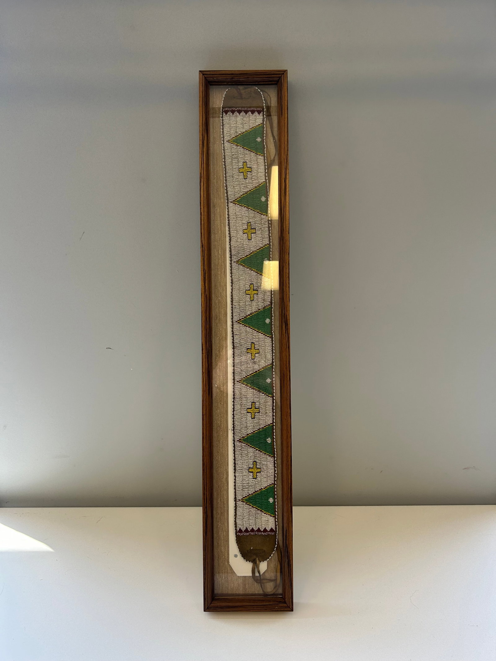 PLAINS INDIAN STYLE BEADED DANCE BELT: THIS IS A DECORATIVE HANDCRAFTED DANCE BELT DISPLAYED IN AN ATTRACTIVE CASE , CHARACTERISTIC OF THE PLAINS INDIANS STYLE HIDE WITH INTRICATE HANDSEWN GLASS BEADWORK (BELT 36'LX3.5'W) PROVENANCE: