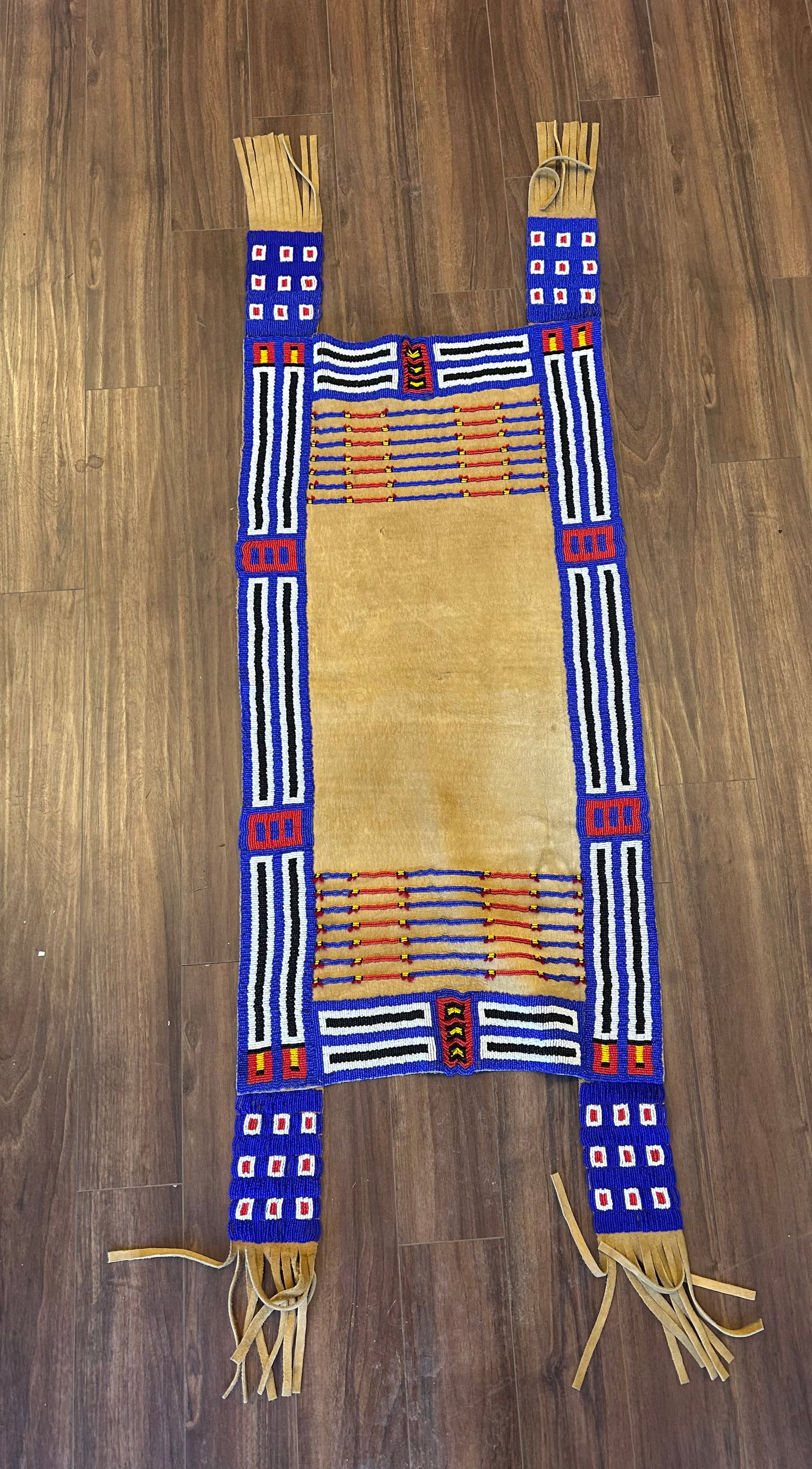 MONUMENTAL PLAINS STYLE BEADED LEATHER PANEL: LARGE LATE 20TH CENTURY HAND CRAFTED PLAINS STYLE LEATHER PANEL EXTENSIVELY DECORATED WITH GEOMETRIC LAZY STITCH BEADWORK IN COLBALT BLUE, WHITE, BLACK, RED AND YELLOW GLASS SEED BEADS. CONSTRUCTED