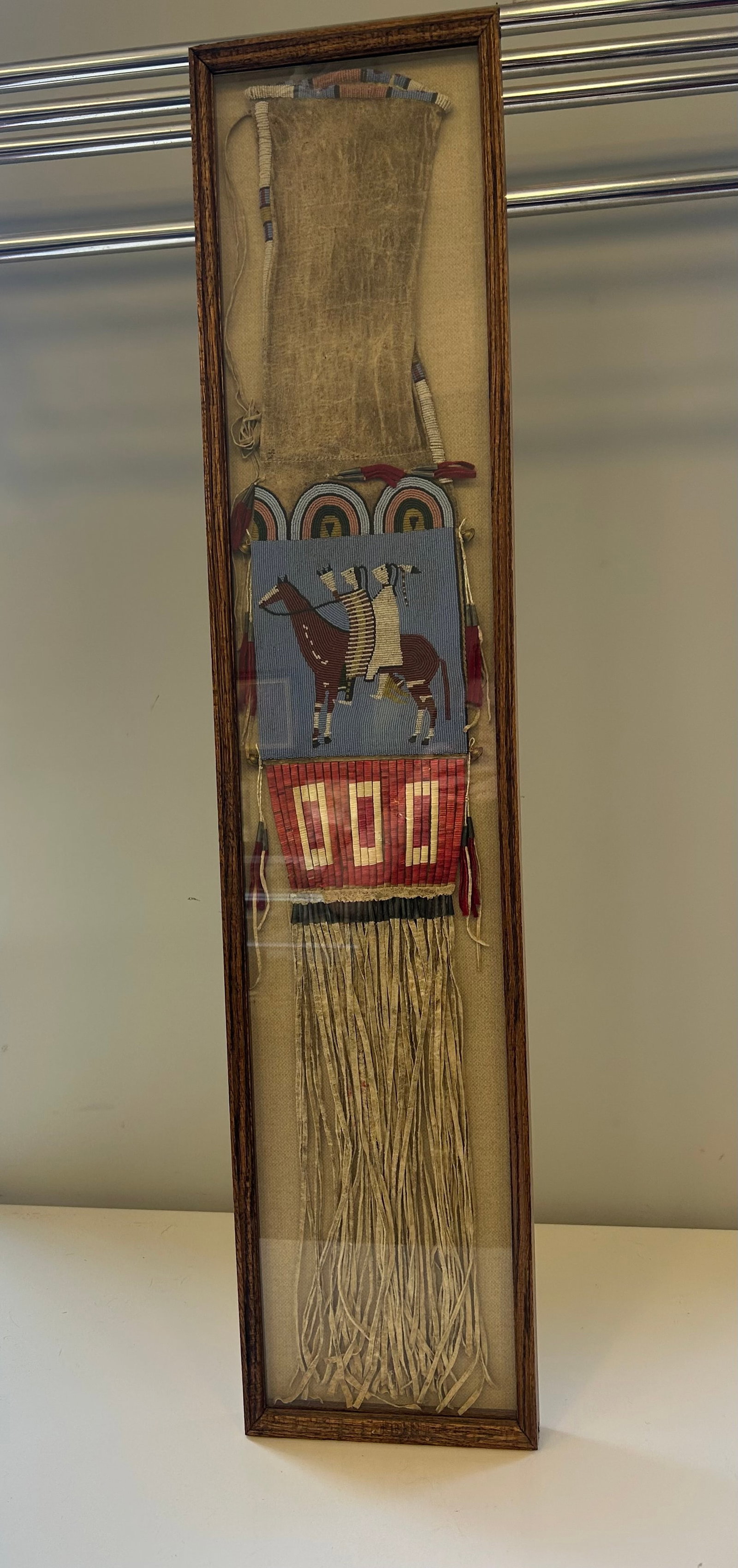 PLAINS INDIAN PICTORIAL BEADED PIPE BAG, CASED: PIPE BAG SIOUX, MINICONJOU TRIBE, GLASS BEADING AND PORCUPINE QUILL WORK, 2 PEOPLE RIDING A HORSE MOTIF, LIKELY LATE 19TH CENTURY, LONG BUCKSKIN FRINGE, PROVENANCE: ESTATE OF DOUG DIVISH, NORTHEAST