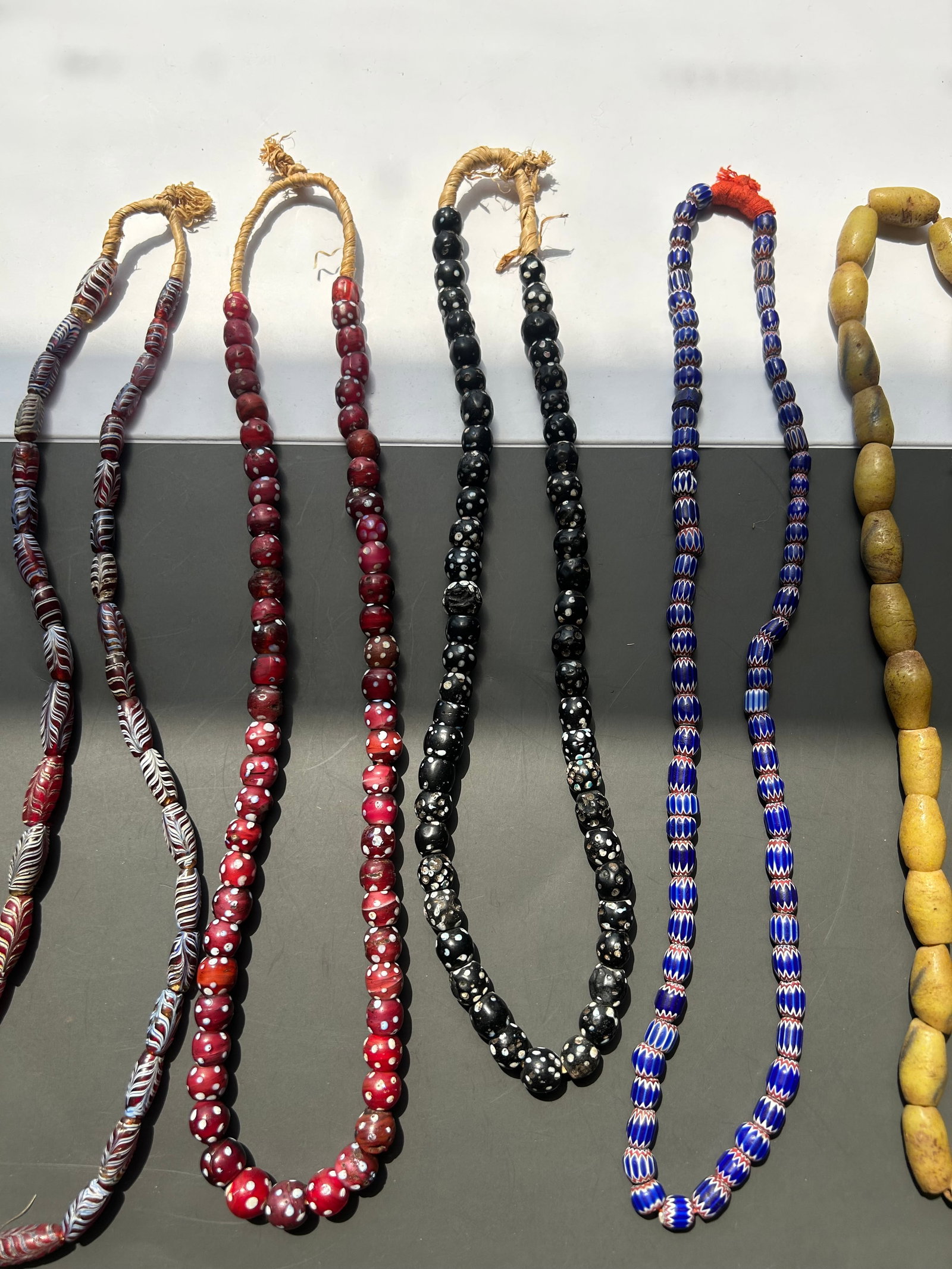 VENETIAN GLASS & STONE BEAD LOT: GROUP LOT CONSISTING OF FIVE STRANDS OF TRADE BEADS, INCLUDING 4 STRANDS OF VENETIAN GLASS BEADS AND ONE STRAND OF LARGE STONE BEADS. CONDITIONS VARIES FROM STRAND TO STRAND WITH EXPECTED WEAR,