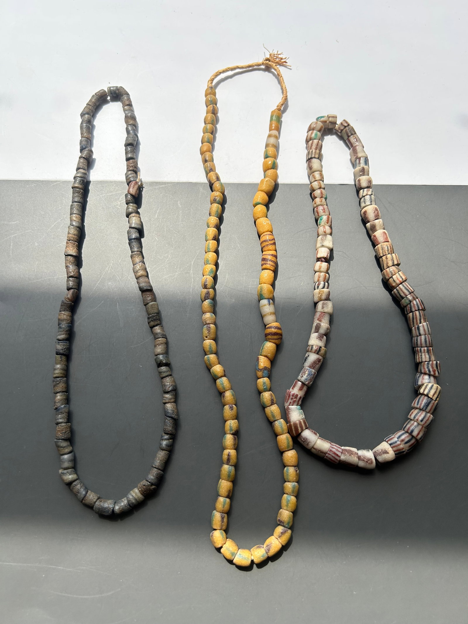 COLLECTION OF 3 ANTIQUE TRADE BEAD STRANDS: AN OUTSTANDING COLLECTION OF THREE ANTIQUE TRADE BEAD STRANDS FEATURING A REMARKABLE ASSORTMENT OF STRIPED, EARTH TONE, AND DECORATED GLASS BEADS. THIS VISUALLY STRIKING GROUP DISPLAYS A WIDE VARIETY