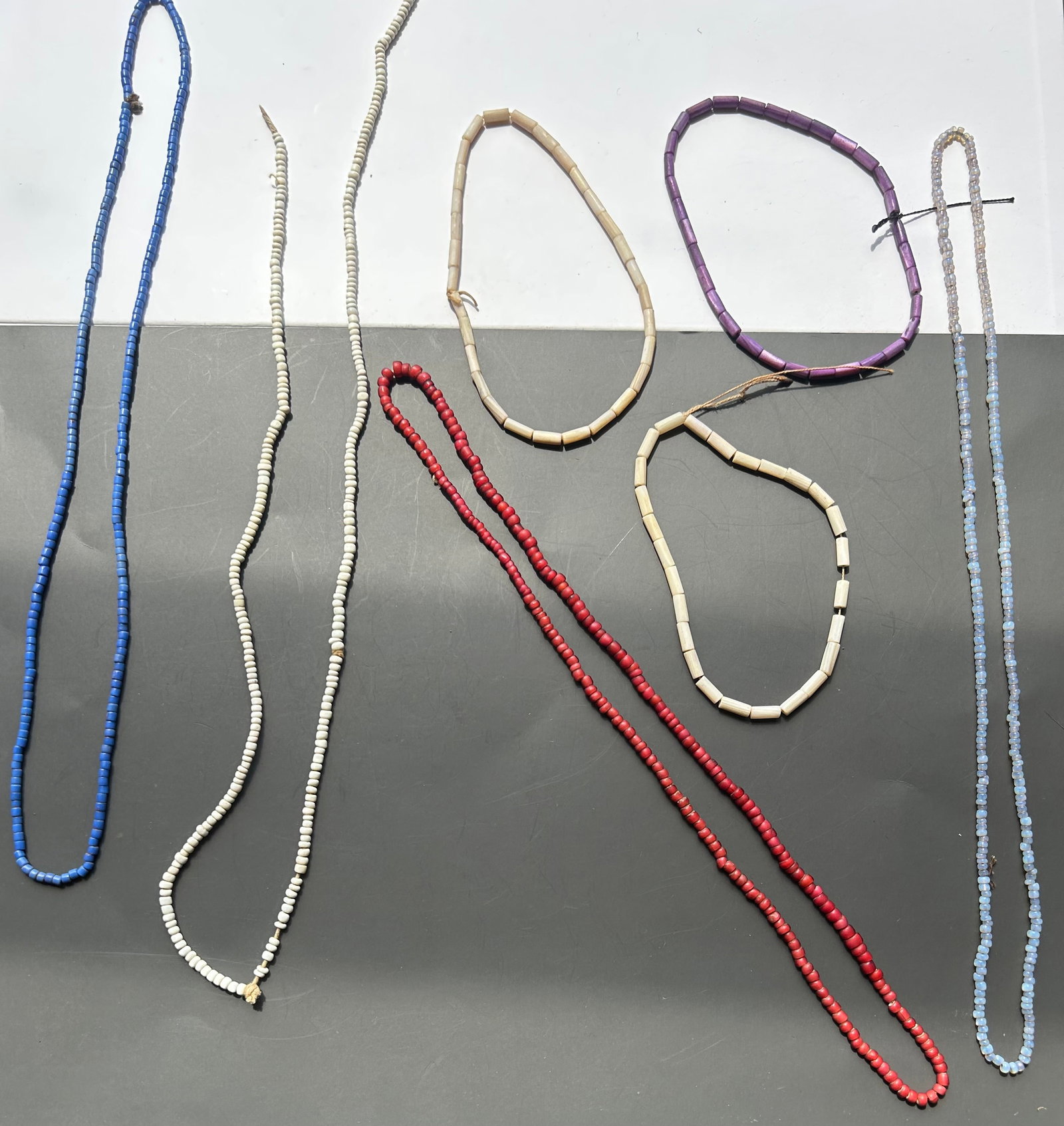 COLLECTION OF 7 ANTIQUE TRADE BEAD STRANDS: AN ATTRACTIVE COLLECTION OF SEVEN ANTIQUE BEAD STRANDS FEATURING A VARIETY OF TRADE BEADS, SEED BEADS, TUBULAR BEADS. THE LOT INCLUDES EXAMPLES IN WHITE, RED (WHITE HEART BEADS), PURPLE, AND A