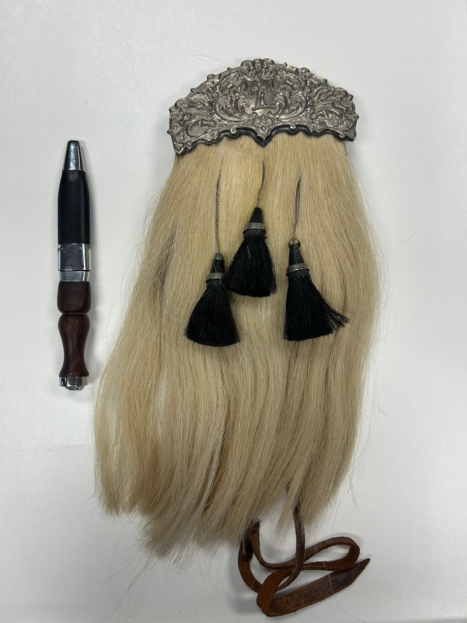 R.G. LAWRIE HIGHLAND SPORRAN & SGIAN-DUBH: STRIKING SCOTTISH HIGHLAND DRESS GROUPING FEATURING AN R.G. LAWRIE FULL DRESS HORSEHAIR SPORRAN WITH ORNATE THISTLE DECORATED METAL CANTLE CENTERED BY A HIGHLANDER FIGURE, LONG LIGHT COLORED HORSEHAIR