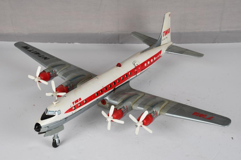TWA DC-7c Battery Operated Airliner: rated 7.5, 24" wingspan, the tin litho body has good color and shine, has small areas of light rust, has light rust at the battery box, looks complete, marked Cragston Toys, Made in Japan.