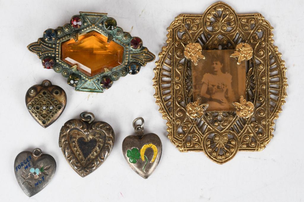 Lot of 6- 4 heart charms, Brooch, & Photo holder: One heart is a locket, one is marked sterling. Brooch has a glass stone in the middle. Holder has a picture of a woman dressed up. All have some wear. Measures 2.25"H x 2"W or smaller.