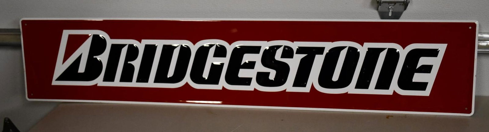 Bridgestone (tires) Metal Sign: rated 8.5, 9.5"x48", SST embossed sign has light wear.