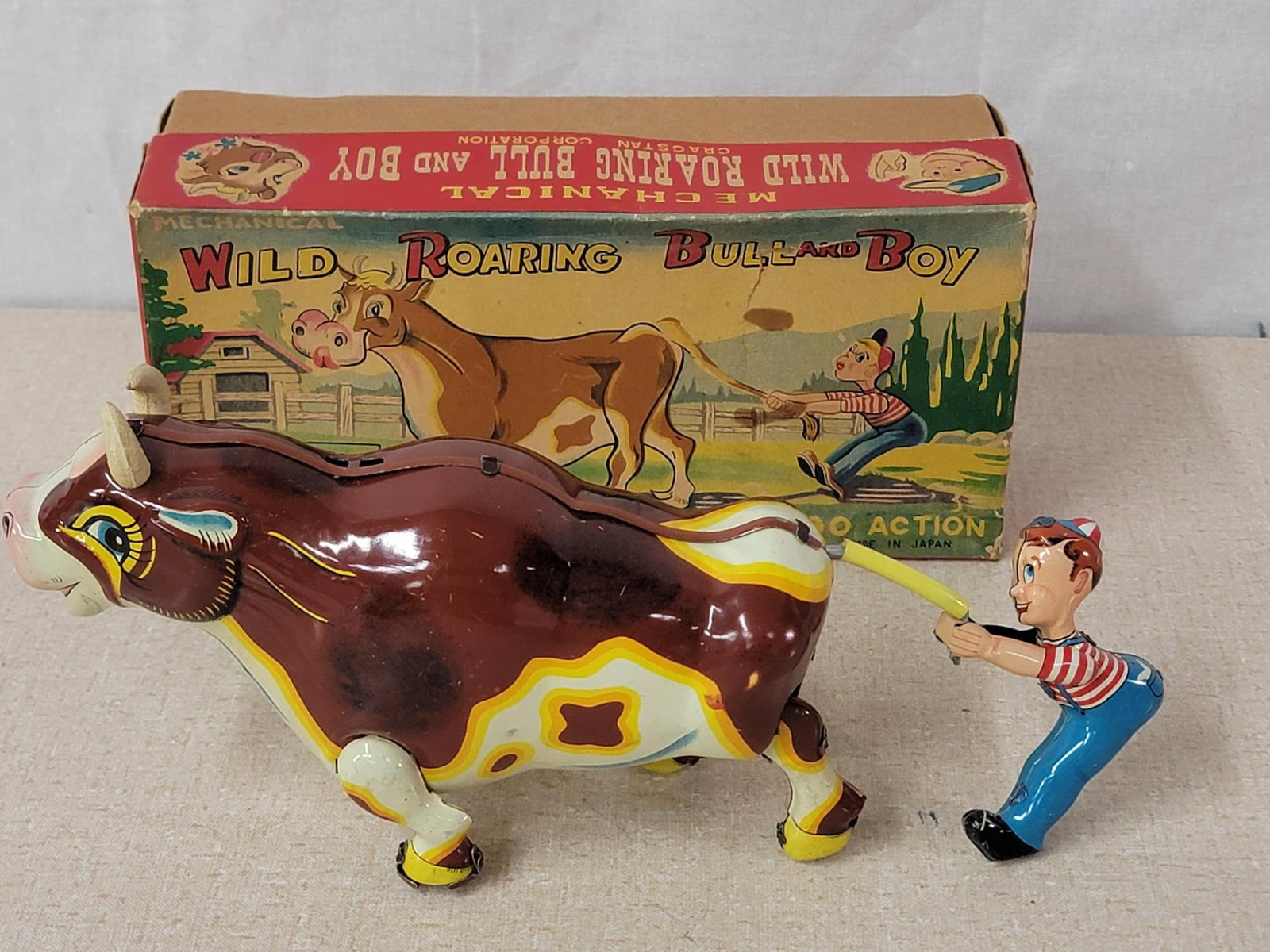 Cragston "Wild Boaring Bull & Boy Japanese Tin Litho Windup Top NIB: rated 9.5, 9.5"L. the tin litho windup toy has excellent color and shine, light wear, works, box is rated 8.