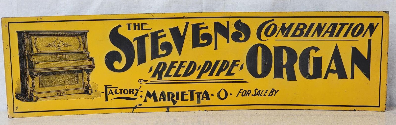 The Stevens Combination Reed Pipe Organ Metal Tacker Sign (TAC): rated 8.75, 5.25"x20", the SST embossed tacker sign has good color and shine, has minor wear and very minor paint loss. TAC #042575