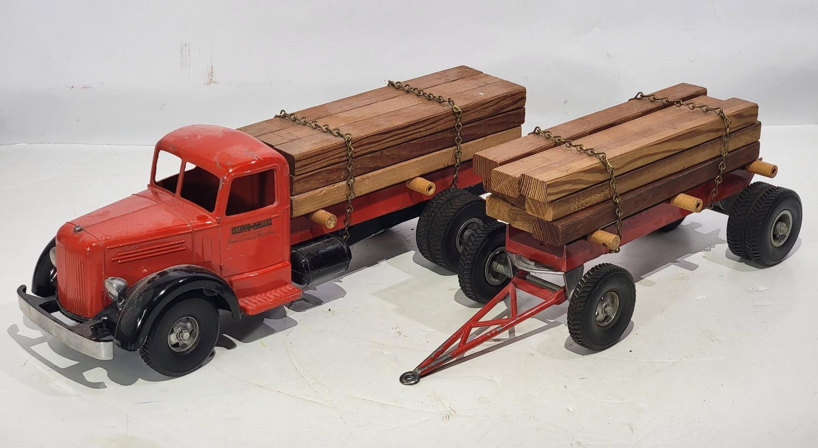 Smith Miller Mack "L" Lumber Truck & Trailer: rated 8.25, 25"L., the diecast truck has good color and shine, has wear and scratches, comes with all the lumber.
