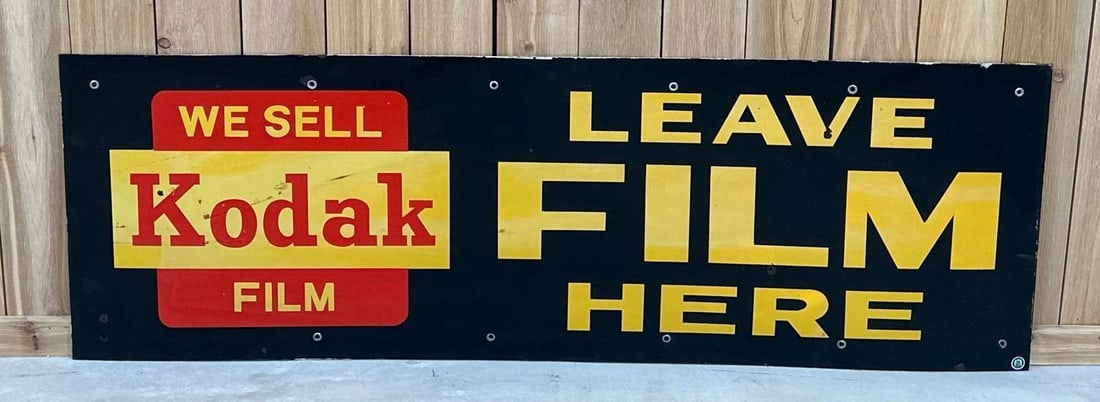 We Sell Kodak Film "Leave Film Here" Porcelain Sign (TAC): rated 7.5, 22"x66", the SSP sign has good gloss, has fading to yellow and some of the red, has a few chips and one hole in the field. TAC #059093